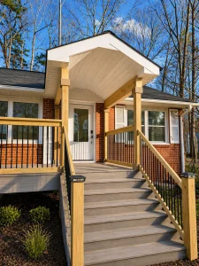 Front exterior of brick ranch with new covered portico entry, natural wood posts and railings — Goff Road renovation in King, NC