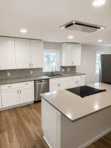Finished kitchen with white shaker cabinets, gray quartz island with built-in cooktop — Goff Road renovation in King, NC