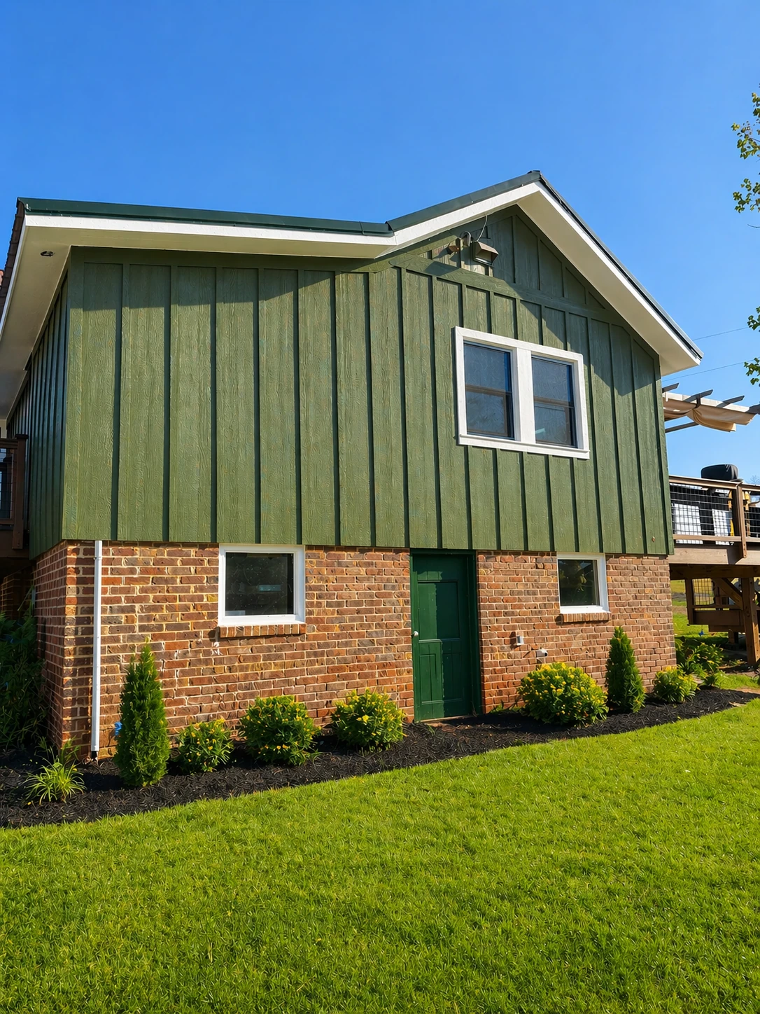Homestead Place rear two-story addition — green board-and-batten over original brick farmhouse with new entry door