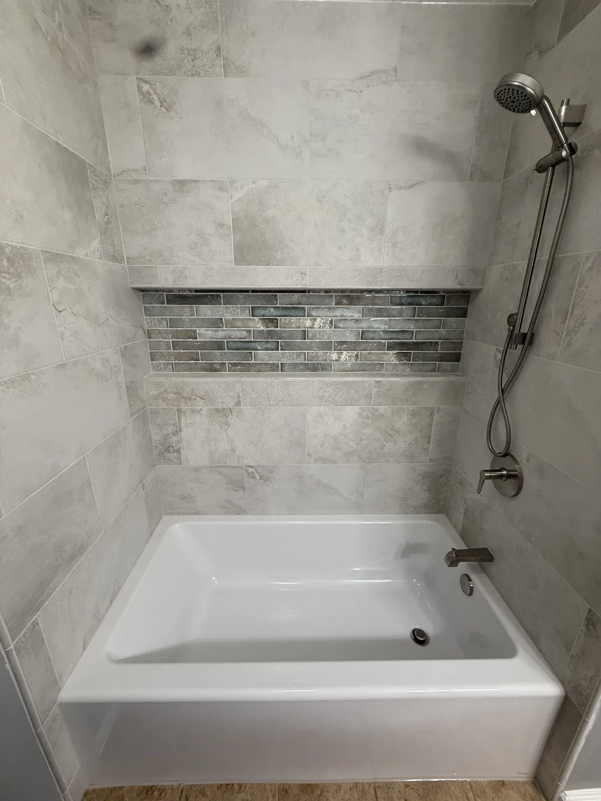 Tub and shower surround in gray large-format tile with a wall-to-wall glass mosaic niche — bathroom remodel by Salem Builders