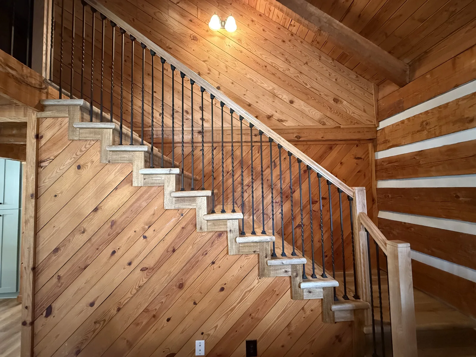 Log cabin staircase with pine treads and iron balusters — Fip Newsome Road renovation in Tobaccoville, NC
